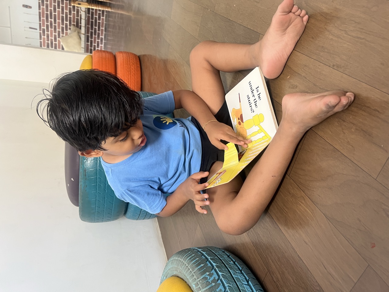 A child sitting cross-legged, absorbed in a picture book