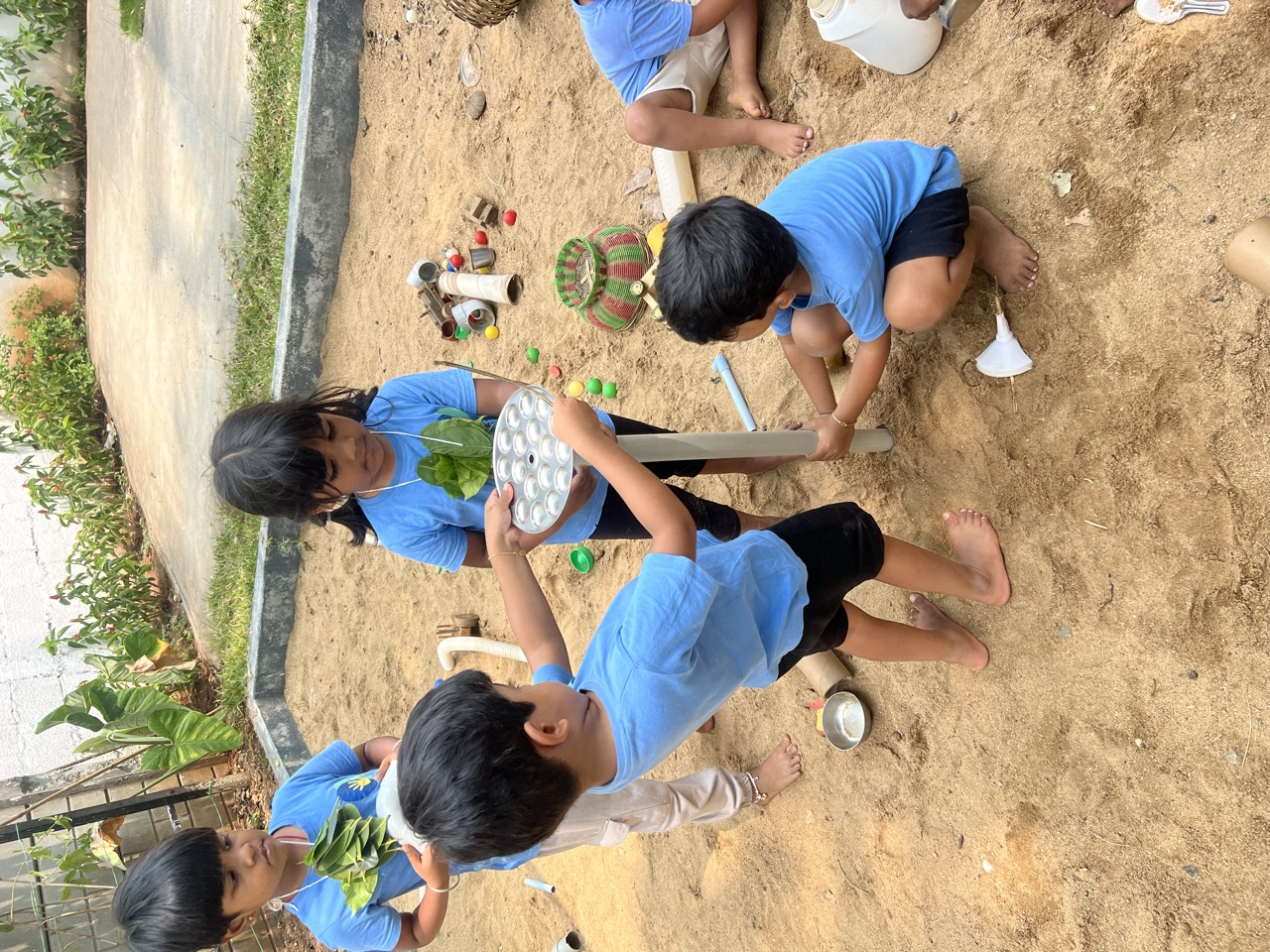 Children cooking up creations at the outdoor mud kitchen in the sandpit
