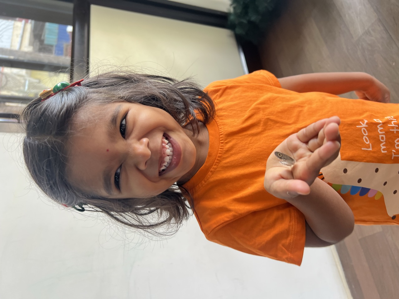 A beaming child showing a tiny treasure held in her hand