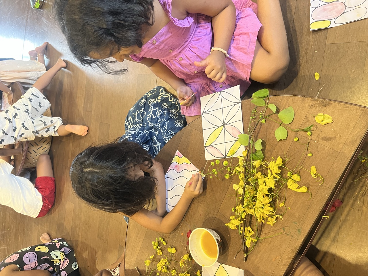 Children making nature art with fresh yellow flowers and paint