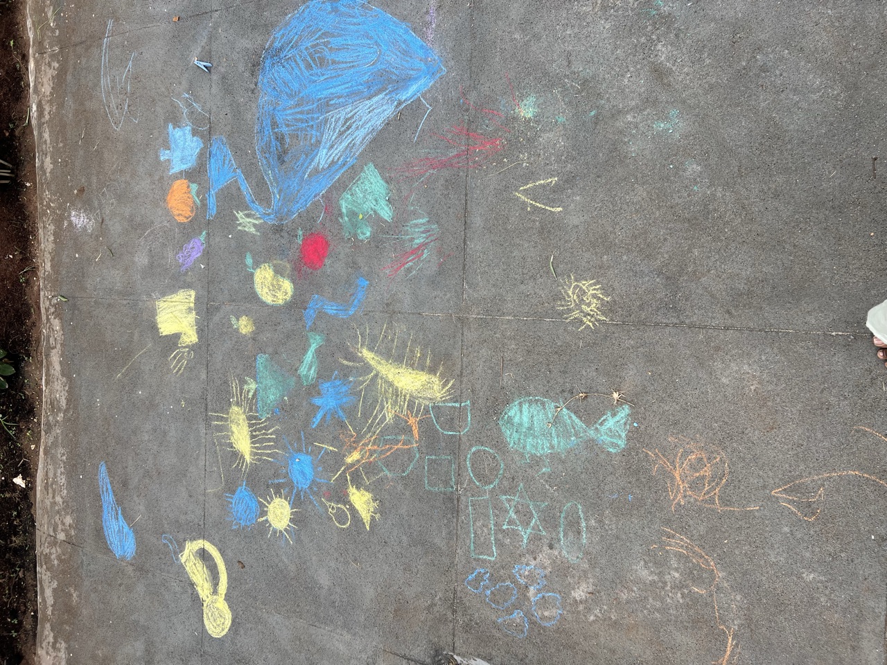 Bright chalk drawings of fish, suns and shapes covering the courtyard floor