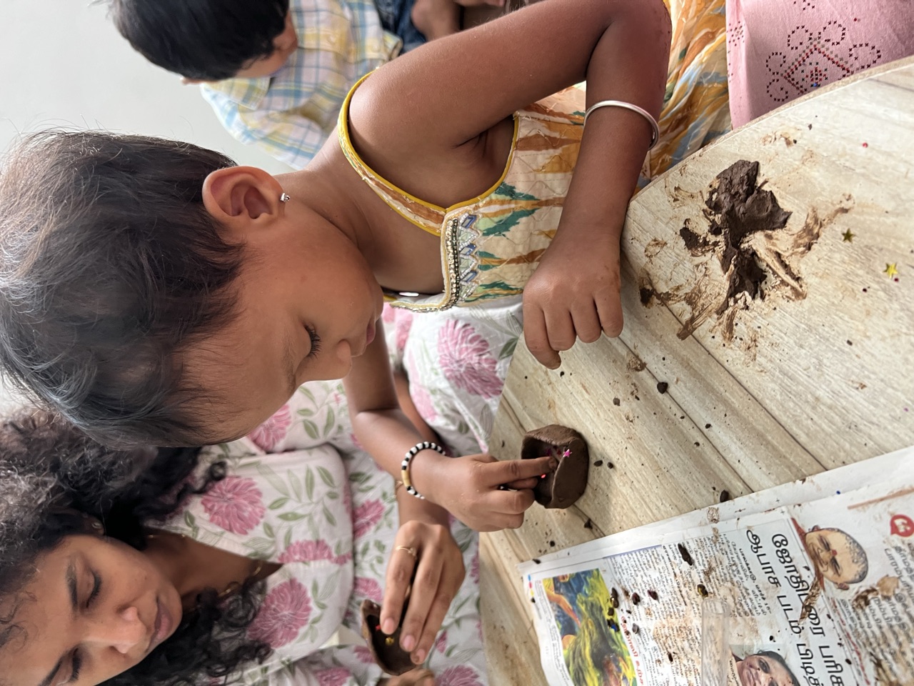 A toddler pressing and shaping clay beside a teacher